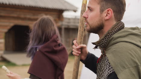 knight and woman with flute stand against tent in courtyard