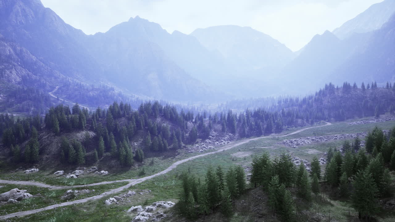 Majestic mountains with winding paths and dense forests under clouds