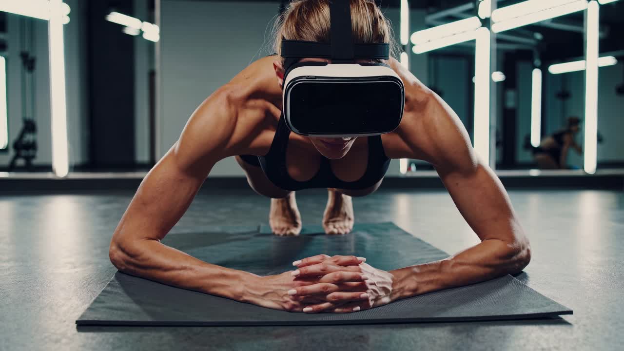 가상 현실 피트니스 애호가 요가 매트에서 도전적인 플랜크 운동을 수행하고 vr 헤드을 착용하고 현대 체육관 환경에서 강렬한 집중력을 보여주고 있습니다.
