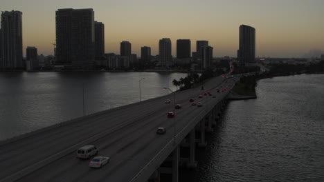 Miami-Bridge-with-cars-passing-by-With-Downtown-Miami-In-The-Background-at-Dusk-Aerial-Shot