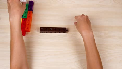 hands assembling colorful linking cubes on a table