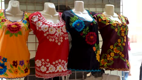 camera turns to left as it moves right showing huipil mexican blouses for women in a shop in merida, mexico