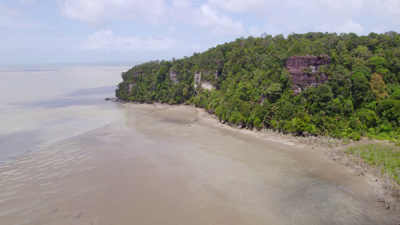 Ripresa aerea delle imponenti scogliere di arenaria del parco nazionale di Bako, ricoperte da una fitta vegetazione verde lungo la costa dell'isola del Borneo, in Malesia