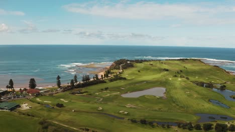 aerial drone shot flying over longreef headland and lush golf course towards beach on pacific ocean