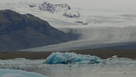 Gletscherlagune-In-Jökulsárlón,-Island,-Mit-Im-Eisigen-Wasser-Schwimmenden-Gletschern-Mit-Schneebedeckten-Bergen-Im-Hintergrund