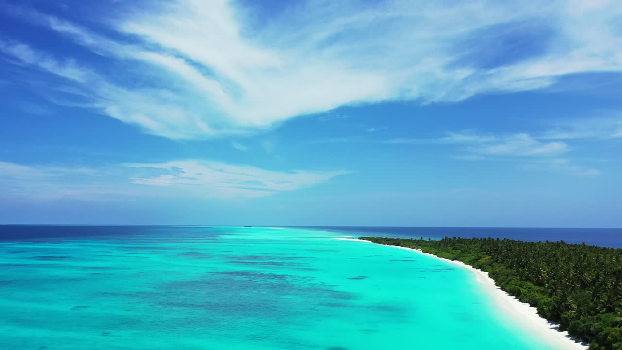 Paradise holiday island with lush vegetation and palm trees, white beach around, washed by calm turquoise lagoon under a bright blue sky with static clouds in Turks and Caicos