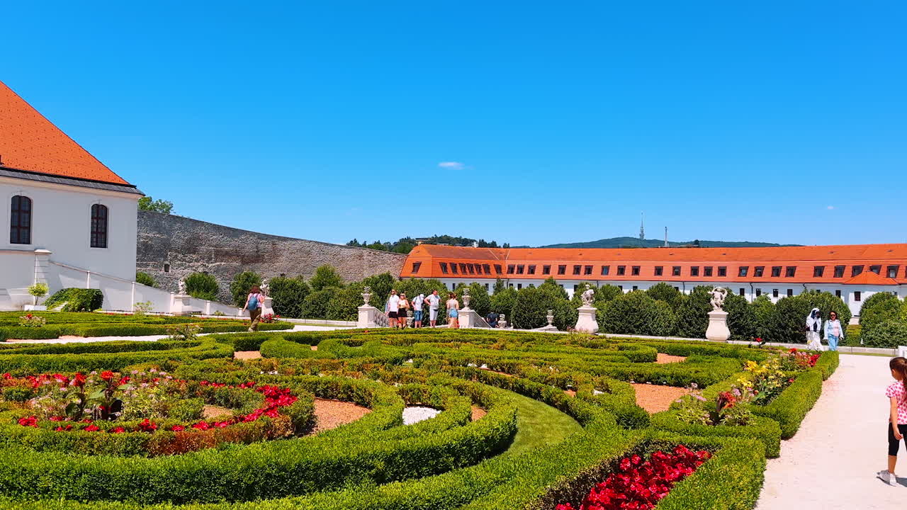 Bratislava, Slovakia, 2 June 2025: Beautiful garden surrounded by old buildings and sculptures. Lovely flower-beds near the Bratislava Castle in Slovakia
