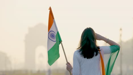 proud indian girl saluting at india gate with indian flag in hand