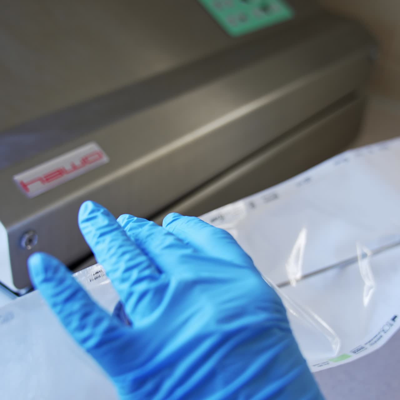 Female medic in blue latex gloves places long metal tool into a plastic bag. Nurse prepares instrument for sterilization in modern equipment