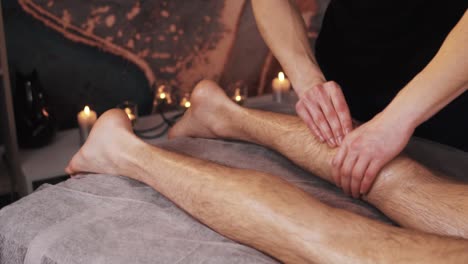 close-up shot, a male massage therapist is massaging the legs of a sporty man