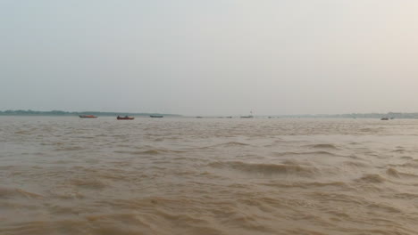 Cinematográfico-Ganges-Todavía-Calma-Fangoso-Marrón-Río-Crucero-Chowk-Canal-Barco-Varanasi-Norte-India-Estado-Antiguo-Ciudad-Santa-Khidkiya-Ghat-Pradesh-Provincia-Paisaje-Gris-Nublado-Tarde-Pan-Izquierda-Movimiento