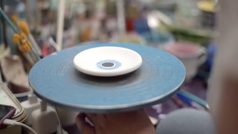 female potter hands paint brushing ceramic plate in workshop for creative and decorative artistic style, closeup
