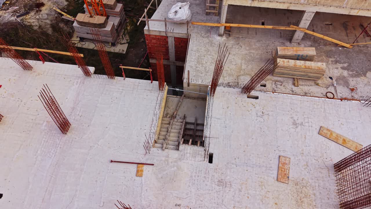 Construction site viewed from above showing rebar and materials scattered