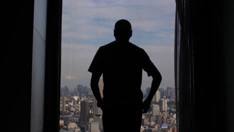 La-Silueta-De-Un-Hombre-Caminando-Hacia-Una-Gran-Ventana-En-Un-Edificio-Alto-Y-Abriendo-Cortinas-Para-Revelar-La-Amplia-Vista-De-La-Metrópolis-De-La-Ciudad