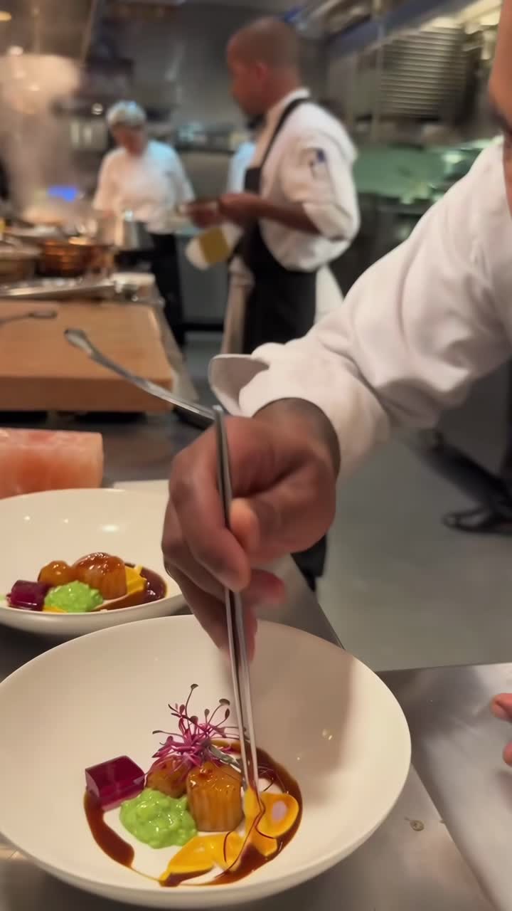 Video ravvicinato di chef che impiattano colorate pietanze gourmet in una vivace cucina