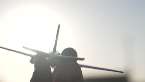 detail of child holding small toy plane during sunset