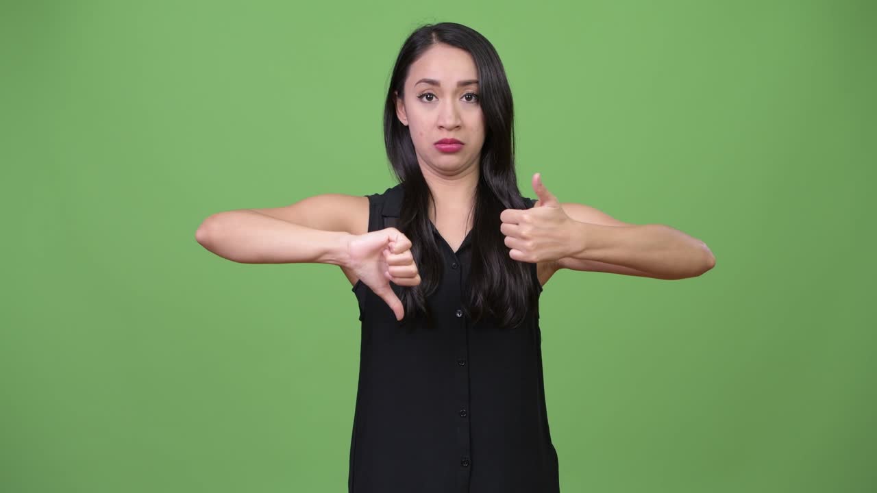 Young beautiful Asian businesswoman choosing between thumbs up and thumbs down