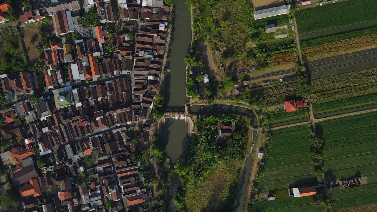 4K aerial footage of a scenic village with a long, winding river flowing through lush green landscapes. Perfect for nature, travel, and documentary projects