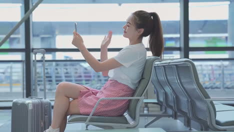 positive businesswoman with luggage sitting on lounge play tablet computer while waiting for boarding of plane in airport, passenger traveler woman in waiting room check social media on mobile phone