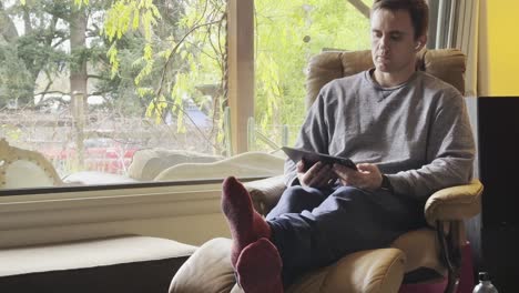 a man working on his tablet is sitting in his living room