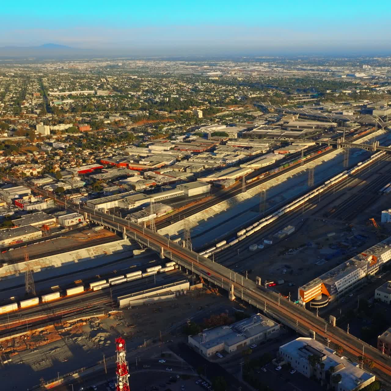 Cement canal for Los Angeles River crossed by bridges for transport. Cityscape from aerial perspective on sunny day