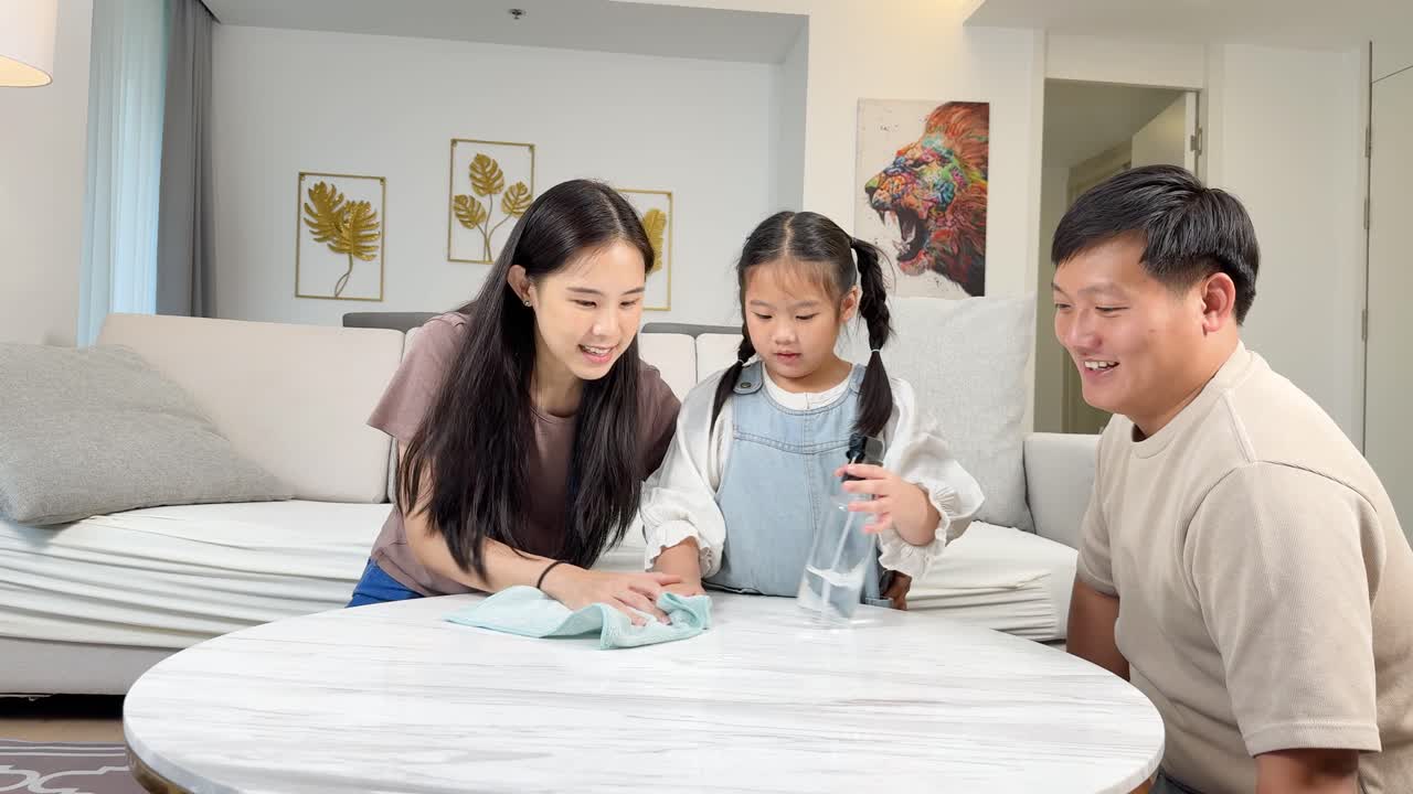Happy family cleaning table together in bright, cozy living room, promoting teamwork and joy