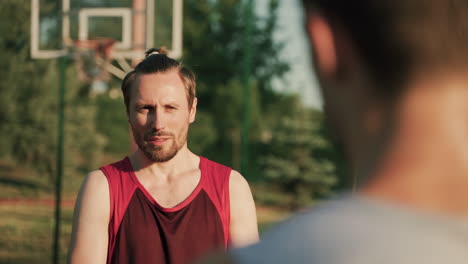 portrait of a serious handsome sportsman talking to his friend, standing in front of him in blurred foreground