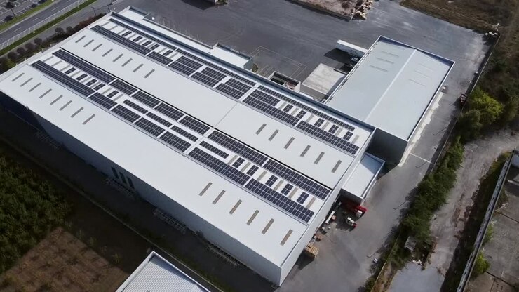 Lagerbygning med hvidt tag fyldt med solpaneler, set fra fugleperspektiv