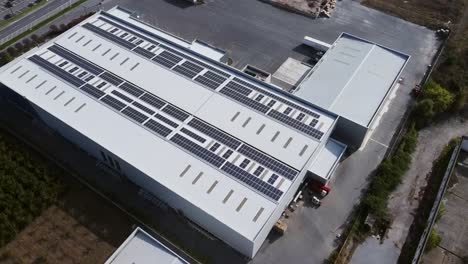 warehouse white roof packed with solar panels, aerial bird’s eye view