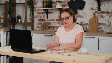 mature woman counting coins on kitchen table