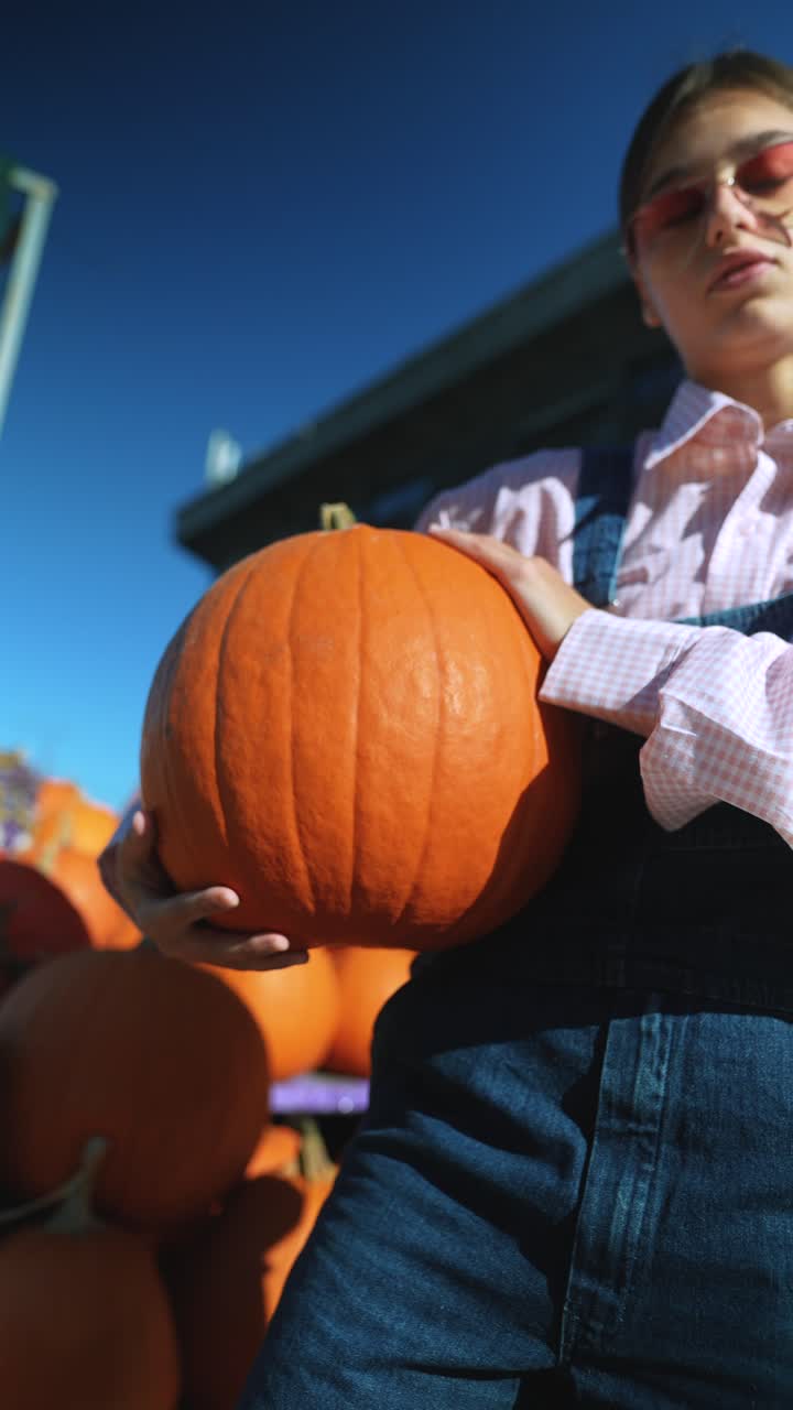 adolescente sosteniendo una gran calabaza en un festival de otoño