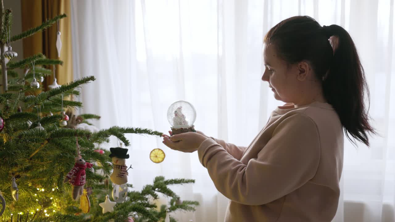 한 소녀가 크리스마스 글로브의 열를 돌려서 활성화하고 있습니다.