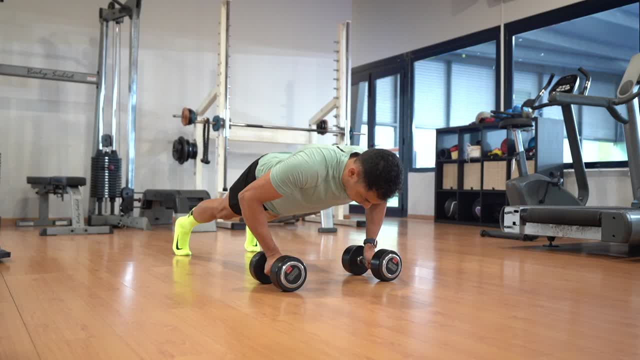Man doing push-ups with dumbbells in the gym