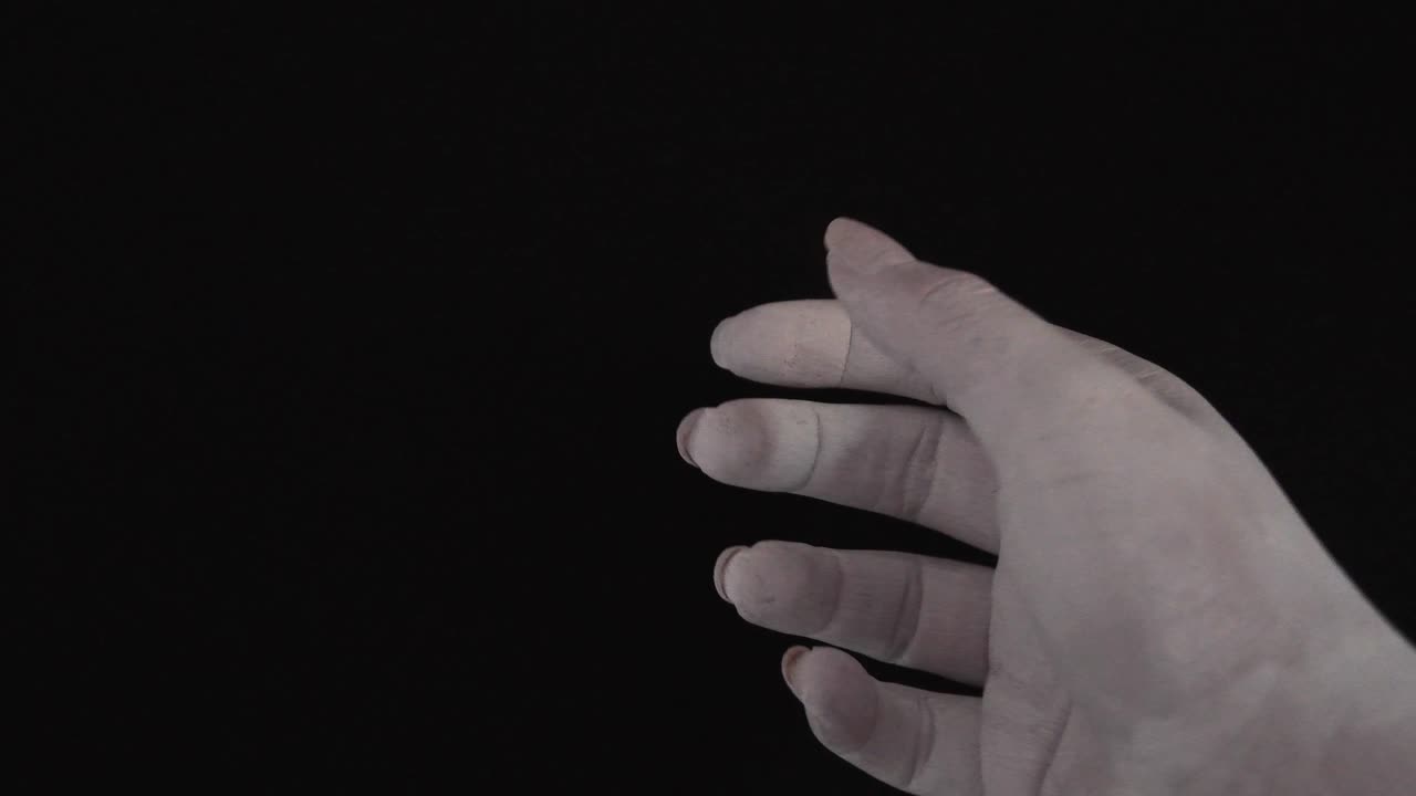 검정색 배경에서 부드럽게 움직이는 흰색으로 칠해진 젊은 여성 손