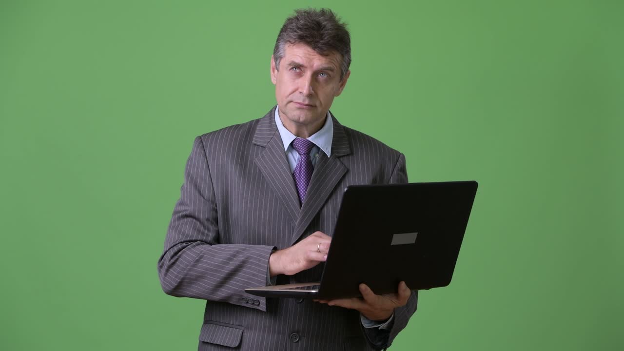 hombre de negocios maduro y guapo contra un fondo verde