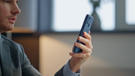 office guy holding smartphone reading message at workplace closeup. happy man