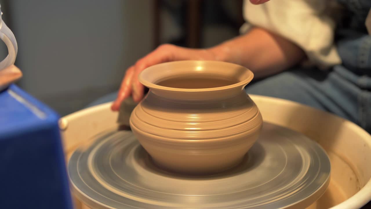 mujer hace una olla en una rueda de cerámica en un taller, cámara lenta