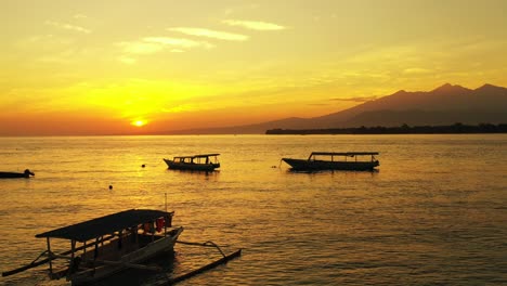 Fishing-boat-floating-on-golden-lagoon-water-under-a-bright-sky-at-sunset-in-Gili-Islands,-Indonesia