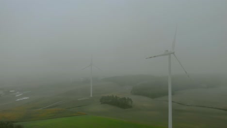 luftaufnahmen aus der nähe von windpark, windmühle bei nebel, graue landschaft drumherum, erneuerbare energie auf freiem feld, unten naturlandschaft, grüne energie ist wichtig