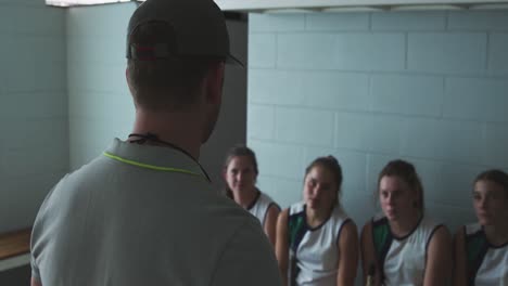 Hockey-coach-talking-with-female-players-in-locker-room
