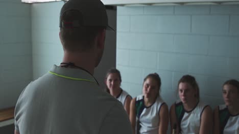 hockey coach talking with female players in locker room