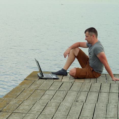 man on the pier working on a laptop
