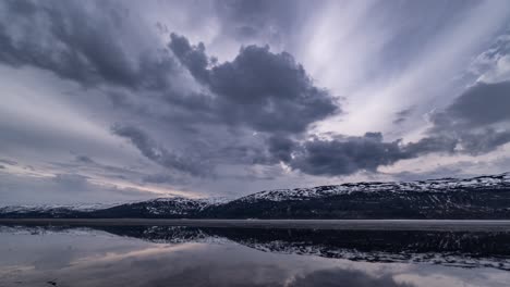 inky clouds forming and flying over the icy lake