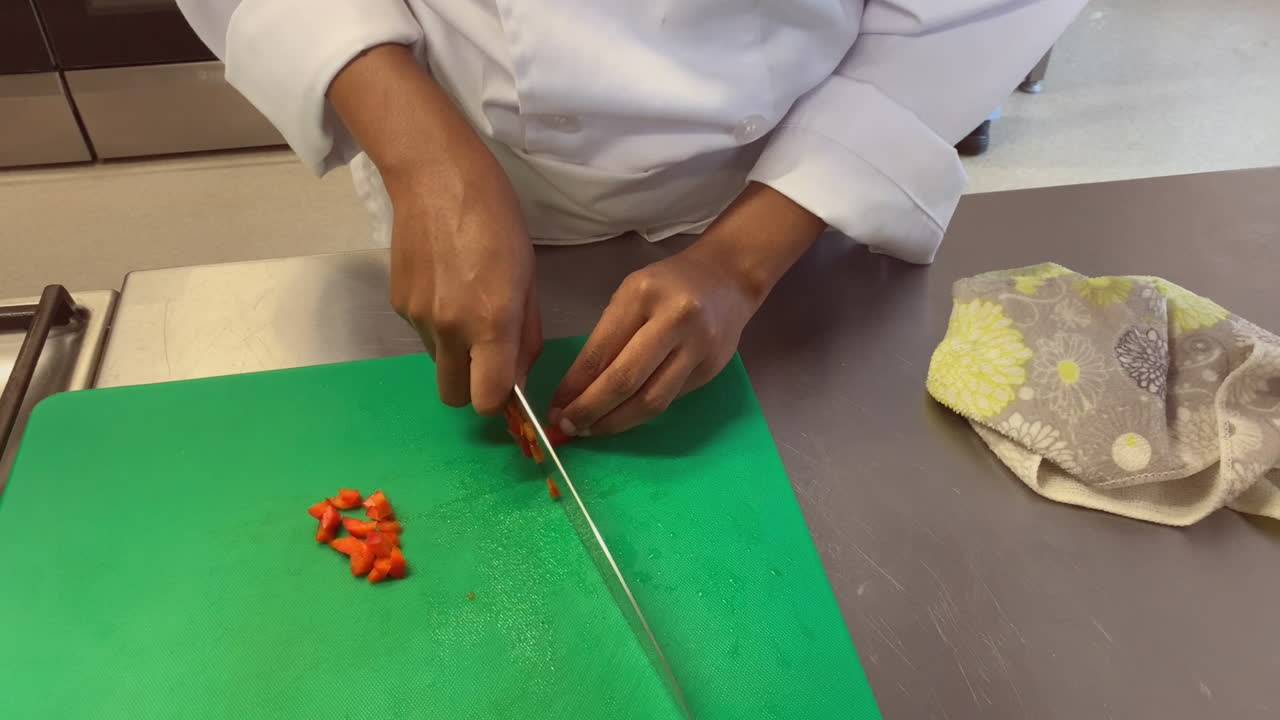 High angle view of young chef chopping red bell pepper in meal prep