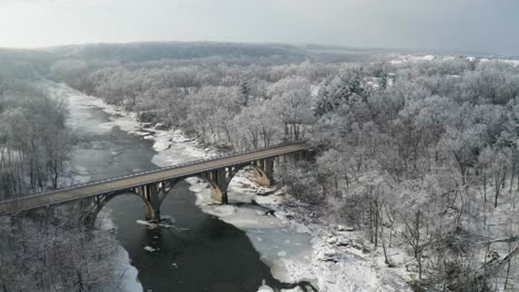 arch bridge over frozen river in foresty area