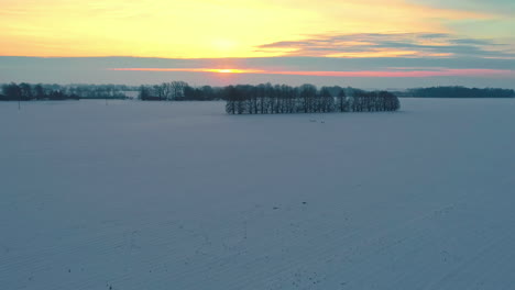 bright golden sunrise on a cloudless winter day across a snowy field