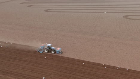 aerial anti-clockwise wider tracking shot of a tractor as it ploughs a field, aberdeenshire, scotland