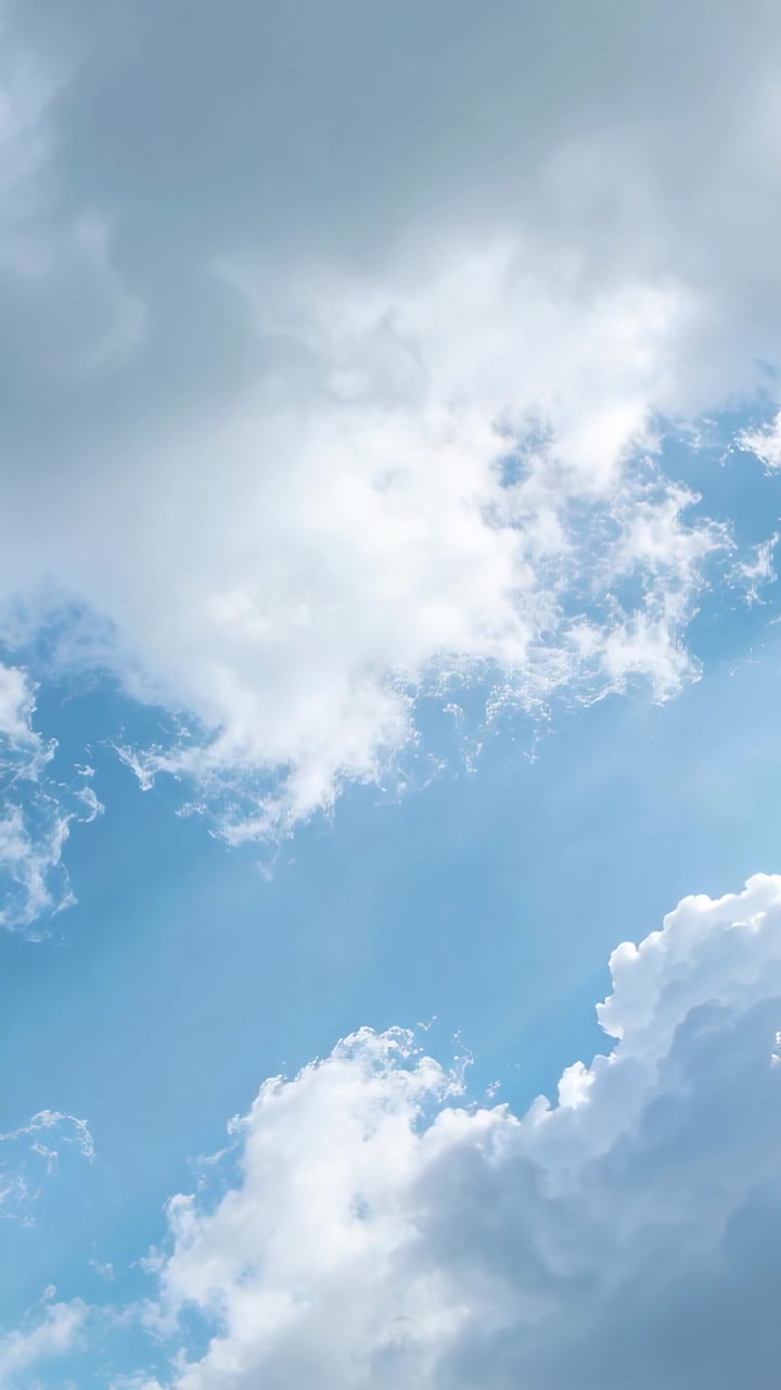 Video verticale: Nuvola cumuliforme alla deriva che si dirada, rivelando raggi di sole nel cielo mentre il sole filtra.