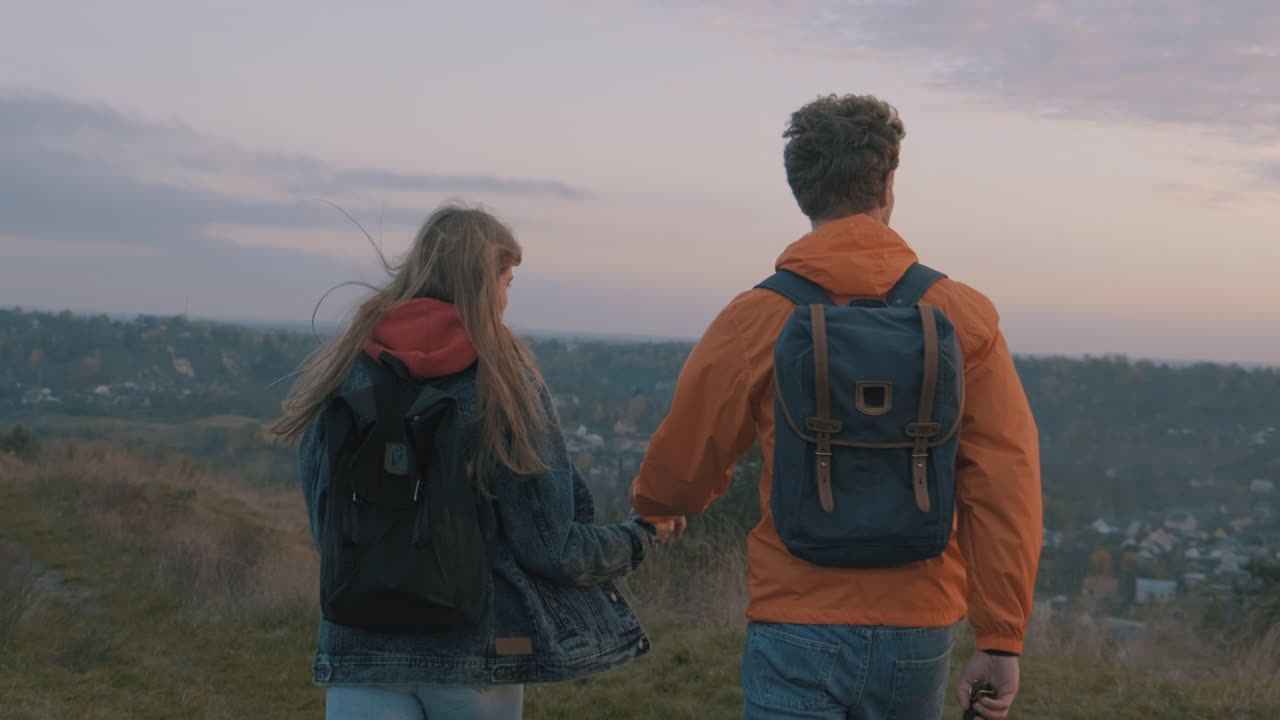 молодые мужчина и женщина в походе с рюкзаками достигают вершины горы