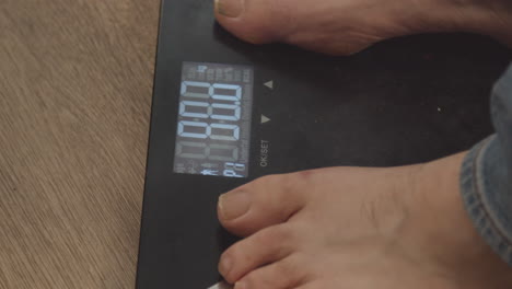 extreme close up of bare feet stepping on weight scale